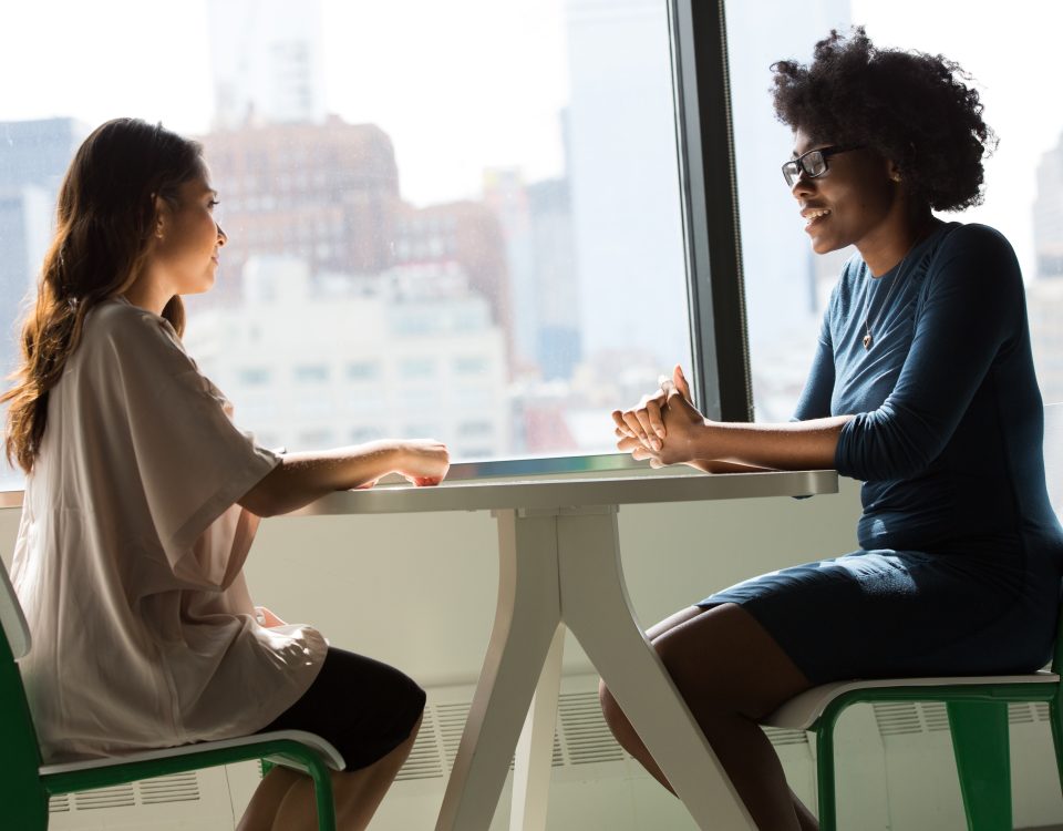 Duas mulheres sentadas frente a frente, conversando